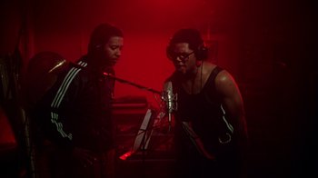 Movie still from “Krush Groove” (1985), directed by Michael Schultz – Two men in a recording studio , one of them wearing headphones and one of the men is wearing a black tank top; Medium shot, Low angle