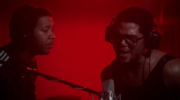 Movie still from “Krush Groove” (1985), directed by Michael Schultz – Two young men are talking in front of microphones in front of a red background; Close Up shot, Low angle