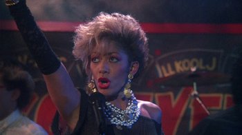 Movie still from “Krush Groove” (1985), directed by Michael Schultz – A woman in a black dress and a black and white necklace; Close Up shot, Low angle