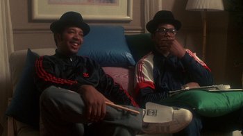 Movie still from “Krush Groove” (1985), directed by Michael Schultz – A couple of men sitting next to each other on top of a couch; Medium shot, Low angle