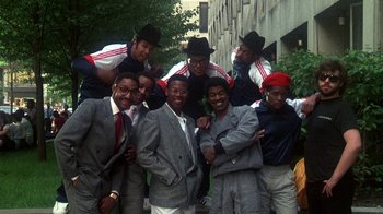 Movie still from “Krush Groove” (1985), directed by Michael Schultz – A group of men standing next to each other in suits; Wide shot, Low angle