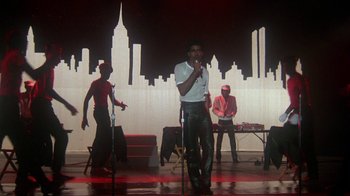 Movie still from “Krush Groove” (1985), directed by Michael Schultz – A group of people on a stage with a microphone; Wide shot, Low angle