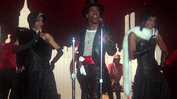 Movie still from “Krush Groove” (1985), directed by Michael Schultz – A man in a leather jacket singing into a microphone; Medium shot, Low angle