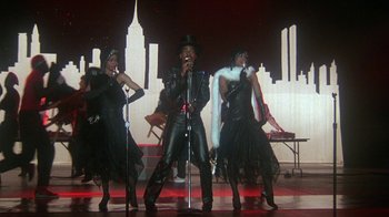 Movie still from “Krush Groove” (1985), directed by Michael Schultz – A group of men and women performing on a stage; Wide shot, Low angle