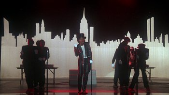 Movie still from “Krush Groove” (1985), directed by Michael Schultz – A group of people standing on a stage with a microphone; Wide shot, Low angle