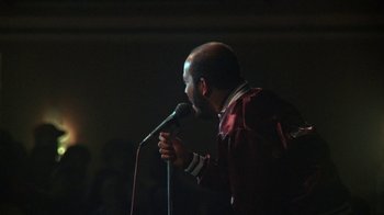Movie still from “Krush Groove” (1985), directed by Michael Schultz – A man with a beard is speaking into a microphone; Close Up shot, Low angle