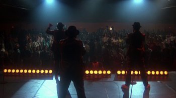 Movie still from “Krush Groove” (1985), directed by Michael Schultz – A group of men standing on a stage in front of an audience; Wide shot, Low angle