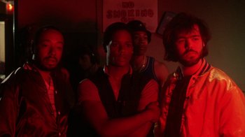 Movie still from “Krush Groove” (1985), directed by Michael Schultz – A group of men standing next to each other in a room; Medium shot, Low angle