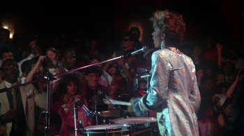 Movie still from “Krush Groove” (1985), directed by Michael Schultz – A man playing drums in front of an audience; Medium shot, Over the shoulder angle