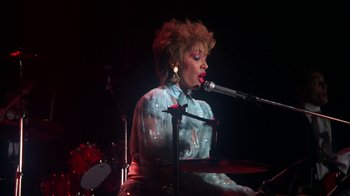 Movie still from “Krush Groove” (1985), directed by Michael Schultz – A woman in a white shirt is playing the drums; Medium shot, Low angle