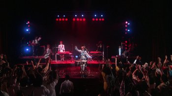 Movie still from “Krush Groove” (1985), directed by Michael Schultz – A group of people on a stage with a microphone; Extreme Wide shot, Low angle