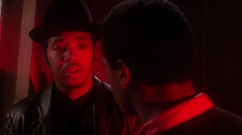 Movie still from “Krush Groove” (1985), directed by Michael Schultz – A man wearing a black hat and a red jacket looking at another man in a red jacket; Close Up shot, Over the shoulder angle