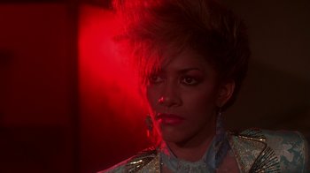 Movie still from “Krush Groove” (1985), directed by Michael Schultz – A woman in a silver jacket with red lights in the background; Close Up shot, Low angle