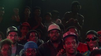 Movie still from “Krush Groove” (1985), directed by Michael Schultz – A group of men sitting next to each other in a room; Medium shot, High angle