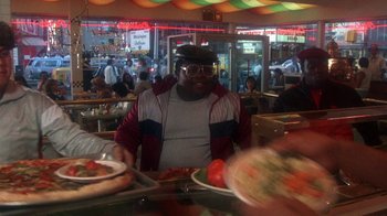 Movie still from “Krush Groove” (1985), directed by Michael Schultz – A man sitting in front of a plate of food; Medium shot, Over the shoulder angle