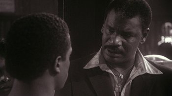 Movie still from “Krush Groove” (1985), directed by Michael Schultz – A black and white photo of a man talking to a young boy; Close Up shot, Over the shoulder angle