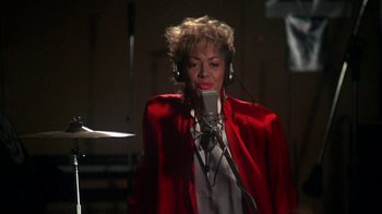 Movie still from “Krush Groove” (1985), directed by Michael Schultz – A woman in a red jacket is singing into a microphone; Close Up shot, High angle