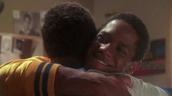 Movie still from “Krush Groove” (1985), directed by Michael Schultz – Two young men hugging each other in a living room; Close Up shot, Over the shoulder angle
