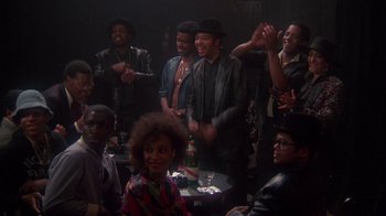 Movie still from “Krush Groove” (1985), directed by Michael Schultz – A group of men and a woman at a party; Medium shot, High angle