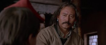 Movie still from “Kundun” (1997), directed by Martin Scorsese – An older man with long hair and a mustache; Close Up shot, Over the shoulder angle