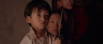 Movie still from “Kundun” (1997), directed by Martin Scorsese – A little boy and a woman are holding a stick; Close Up shot, Over the shoulder angle