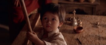 Movie still from “Kundun” (1997), directed by Martin Scorsese – A little boy sitting on the floor looking at the camera; Close Up shot, High angle