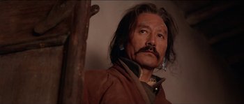 Movie still from “Kundun” (1997), directed by Martin Scorsese – A man with long black hair and a mustache; Close Up shot, Low angle