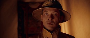 Movie still from “Kundun” (1997), directed by Martin Scorsese – A man wearing a hat is looking at the camera; Close Up shot, Low angle