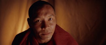 Movie still from “Kundun” (1997), directed by Martin Scorsese – A person wearing a red robe; Close Up shot, Low angle