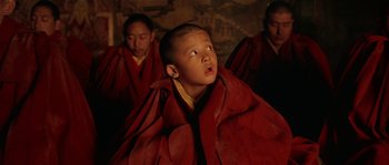 Movie still from “Kundun” (1997), directed by Martin Scorsese – A young boy in a red robe looking up; Close Up shot, Low angle