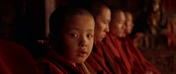 Movie still from “Kundun” (1997), directed by Martin Scorsese – A group of young buddhist monks sitting next to each other; Close Up shot, High angle