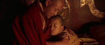 Movie still from “Kundun” (1997), directed by Martin Scorsese – A man and a boy are snuggled up together; Close Up shot, Low angle