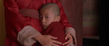Movie still from “Kundun” (1997), directed by Martin Scorsese – A person holding a young boy in a red blanket; Close Up shot, High angle