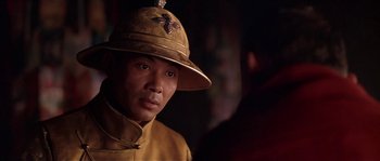 Movie still from “Kundun” (1997), directed by Martin Scorsese – A man wearing a hat and a yellow jacket; Close Up shot, Over the shoulder angle