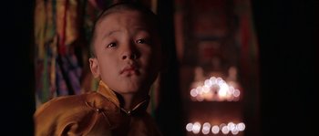Movie still from “Kundun” (1997), directed by Martin Scorsese – A young boy wearing a yellow shirt is looking at the camera; Close Up shot, Low angle