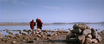 Movie still from “Kundun” (1997), directed by Martin Scorsese – Two monks are walking on the shore of a body of water; Wide shot, Over the shoulder angle
