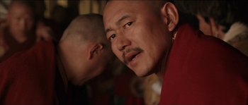 Movie still from “Kundun” (1997), directed by Martin Scorsese – A person with a bald head; Close Up shot, Over the shoulder angle