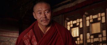Movie still from “Kundun” (1997), directed by Martin Scorsese – A man in a red robe is standing in front of a window; Close Up shot, Low angle