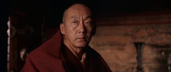 Movie still from “Kundun” (1997), directed by Martin Scorsese – A man in a monk's outfit is looking at the camera; Close Up shot, Low angle