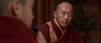 Movie still from “Kundun” (1997), directed by Martin Scorsese – A man in a red and yellow robe looking at a woman in a red and yellow robe; Close Up shot, Over the shoulder angle