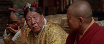 Movie still from “Kundun” (1997), directed by Martin Scorsese – Two people sitting in a living room talking to each other; Close Up shot, Over the shoulder angle