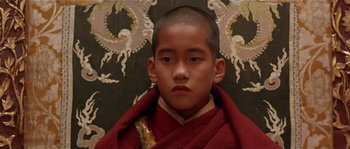 Movie still from “Kundun” (1997), directed by Martin Scorsese – A young boy wearing a red robe with a dragon on the wall behind him; Close Up shot, High angle