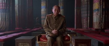 Movie still from “Kundun” (1997), directed by Martin Scorsese – An old man in a military uniform sitting on a chair; Medium shot, High angle
