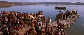 Movie still from “Kundun” (1997), directed by Martin Scorsese – A group of people standing on top of a sandy beach; Extreme Wide shot, High angle