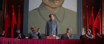 Movie still from “Kundun” (1997), directed by Martin Scorsese – A man standing in front of two other men in front of a painting of mao zedong; Medium shot, Low angle