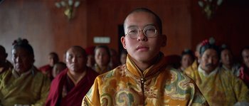 Movie still from “Kundun” (1997), directed by Martin Scorsese – A man in a yellow and red jacket with glasses; Close Up shot, Low angle