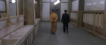 Movie still from “Kundun” (1997), directed by Martin Scorsese – Two men walking down a hall way in a building; Wide shot, High angle