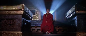Movie still from “Kundun” (1997), directed by Martin Scorsese – A man in a red robe sitting on steps; Wide shot, Low angle