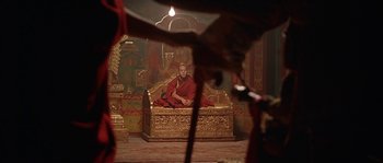 Movie still from “Kundun” (1997), directed by Martin Scorsese – A monk sitting on top of a golden couch; Wide shot, Over the shoulder angle