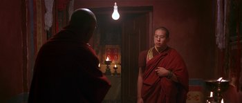 Movie still from “Kundun” (1997), directed by Martin Scorsese – A monk is standing in front of a candle light; Medium shot, Over the shoulder angle